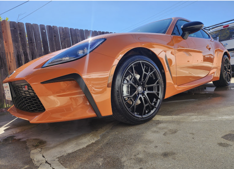Orange sports coupe with freshly cleaned black alloy wheels and dressed tires